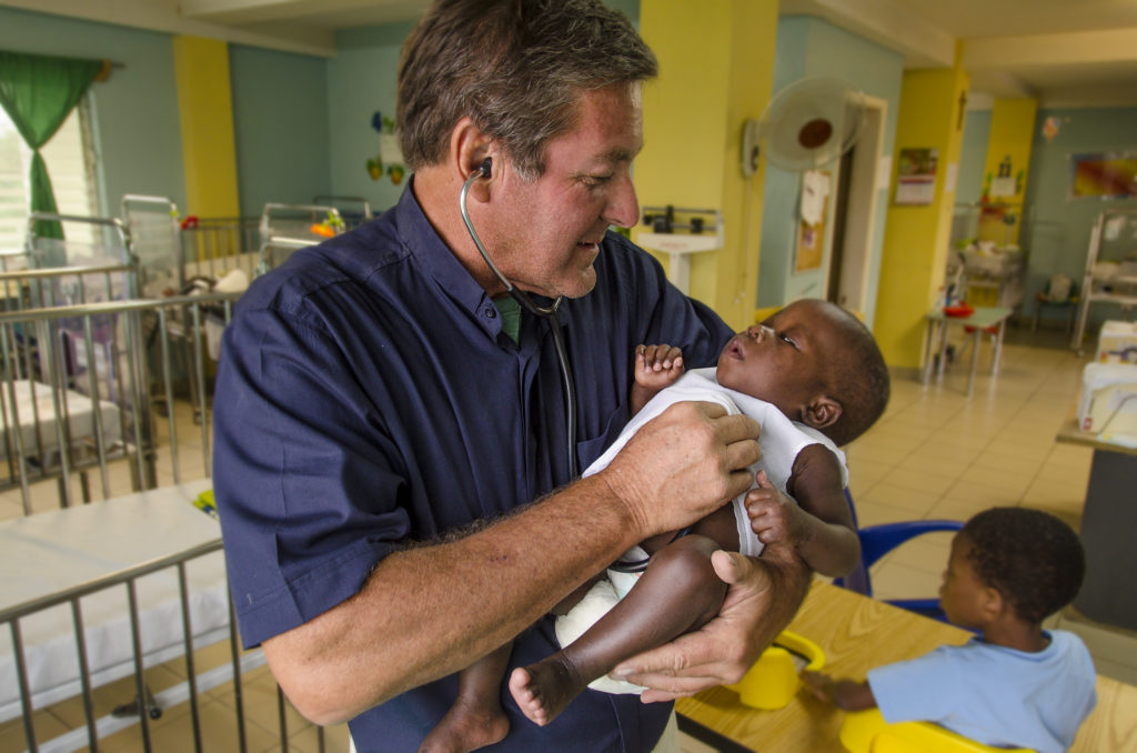 Fr. Rick Frechette attending to a patient at St. Damien Pediatric Hospital